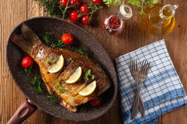 Kızarmış sazan. Limon ve vişneli domatesle servis edilir. Kızarmış balık için tavada servis edilmiş..
