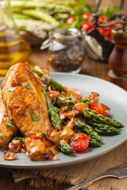 Kızarmış tavuk göğsü, kuşkonmazla servis edilen domates sosu, kurutulmuş domates. Ön görünüm.