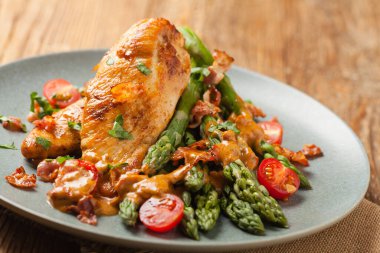 Kızarmış tavuk göğsü, kuşkonmazla servis edilen domates sosu, kurutulmuş domates. Ön görünüm.