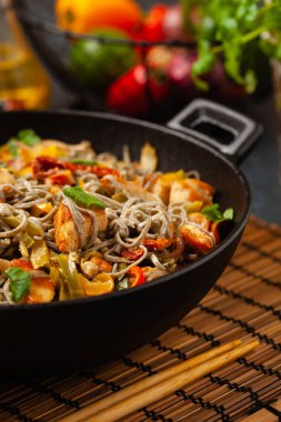 Siyah susamlı buğday eriştesi, tavuk ve sebzeli tavada kızartılmış. Ön görünüm.