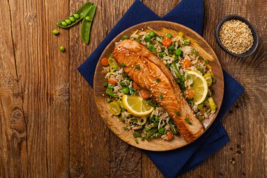 Asya yemeği. Pirinç ve sebzeli kızarmış somon. Susam tohumları serpiştirilmiş. Üst Manzara. Doğal arkaplan. 