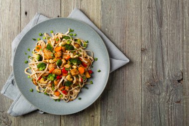 Tavuk, brokoli ve havuçla karıştırılmış makarna. Üst Manzara. Gri ahşap arka plan. Gri bir tabakta servis edilir..