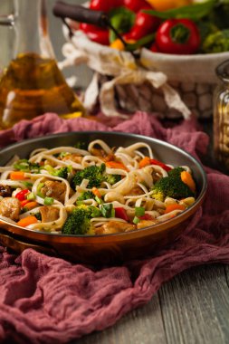 Tavuk, brokoli ve havuçla karıştırılmış makarna. Kızartma tavasında servis edilir..