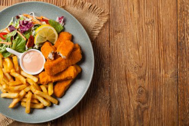 Patates kızartmalı balık ve gri tabakta salata. Üst görünüm.