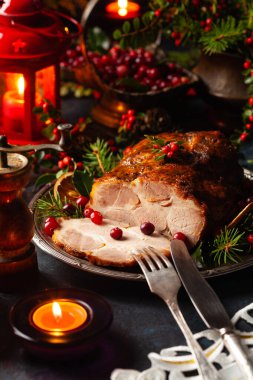 Noel tarzında kızarmış domuz boynu. Koyu lacivert arka plan. Noel aksesuarları. Arka planda mumlar ve fenerler..