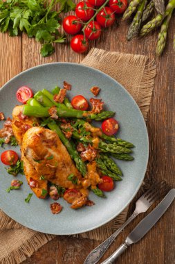 Kızarmış tavuk göğsü, kuşkonmazla servis edilen domates sosu, kurutulmuş domates. Üst görünüm.