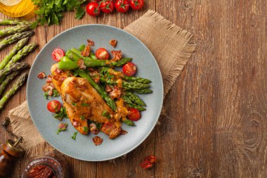 Kızarmış tavuk göğsü, kuşkonmazla servis edilen domates sosu, kurutulmuş domates. Üst görünüm.