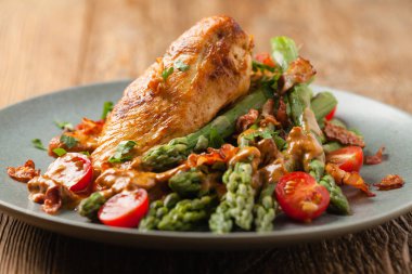 Kızarmış tavuk göğsü, kuşkonmazla servis edilen domates sosu, kurutulmuş domates. Ön görünüm.