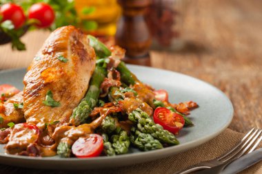 Kızarmış tavuk göğsü, kuşkonmazla servis edilen domates sosu, kurutulmuş domates. Ön görünüm.