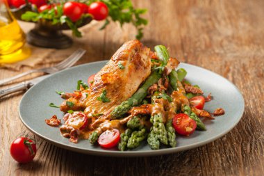 Kızarmış tavuk göğsü, kuşkonmazla servis edilen domates sosu, kurutulmuş domates. Ön görünüm.