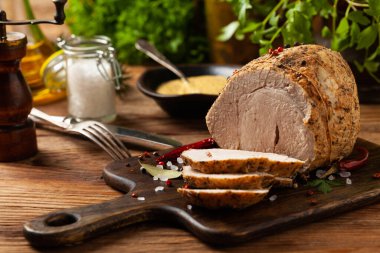 Çıtır, pişmiş jambon. Ahşap bir tahtada baharatlarla servis edilir. Ön görünüm.