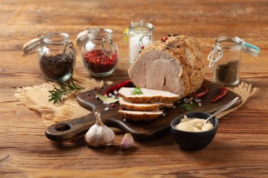 Çıtır, pişmiş jambon. Ahşap bir tahtada baharatlarla servis edilir. Ön görünüm.