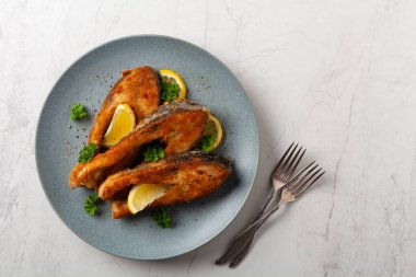 Parça parça sazan balığı, gri bir tabakta servis ediliyor. Parlak bir altyapısı var. Üst görünüm.