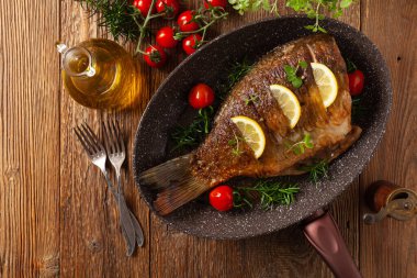 Kızarmış sazan. Limon ve vişneli domatesle servis edilir. Kızarmış balık için tavada servis edilmiş..