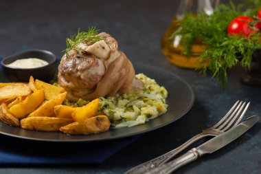 Kaynamış eklem, lahana ve fırında patates ile servis edilir. Ön manzara. Koyu mavi arka plan. Koyu mod. 