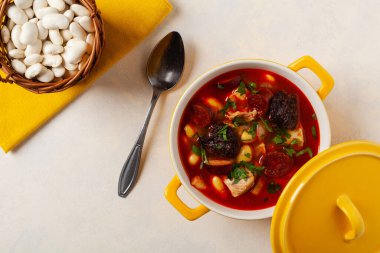 Geleneksel İspanyol gulaş çorbası. Fabada Asturiana. Kapaklı sarı kilden bir çömlekle servis edilmiş. Üst görünüm.