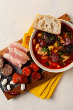 Geleneksel İspanyol gulaş çorbası. Fabada Asturiana. Kapaklı sarı kilden bir çömlekle servis edilmiş. Üst görünüm.