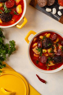 Geleneksel İspanyol gulaş çorbası. Fabada Asturiana. Kapaklı sarı kilden bir çömlekle servis edilmiş. Üst görünüm.
