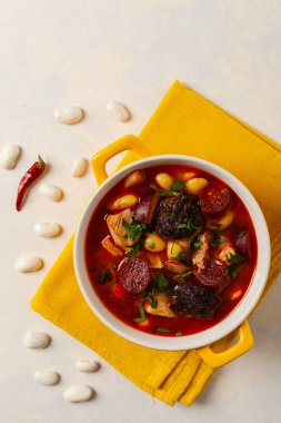 Geleneksel İspanyol gulaş çorbası. Fabada Asturiana. Kapaklı sarı kilden bir çömlekle servis edilmiş. Üst görünüm.