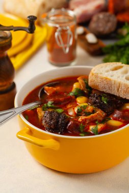 Geleneksel İspanyol gulaş çorbası. Fabada Asturiana. Kapaklı sarı kilden bir çömlekle servis edilmiş. Ön görünüm.