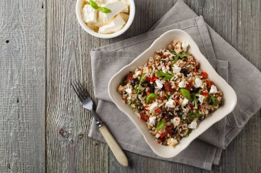 Kırmızı pirinçli moda öğle yemeği, sebze ve sebze karışımı. Üst Manzara. Gri ahşap arka planda beyaz kasede servis ediliyor.. 