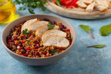 Mısır gevreği, pancar kökü ve tavukla moda bir öğle yemeği. Mavi boyalı arka planda bir kasede servis edilmiş. Ön görünüm. 