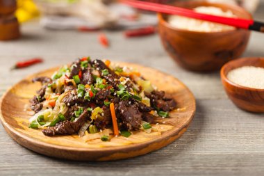 Geleneksel Kore Bulgogi yemeği. İnce dilimlenmiş, ızgara sığır eti, pirinç ve sebzelerle servis edilmiş. Ön manzara. Doğal ahşap zemin.