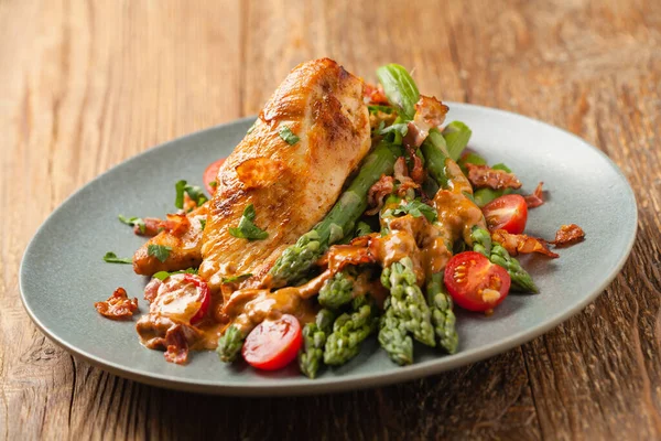 Kızarmış tavuk göğsü, kuşkonmazla servis edilen domates sosu, kurutulmuş domates. Ön görünüm.