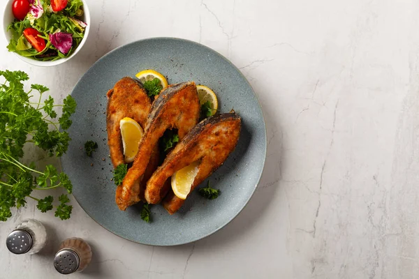 Parça parça sazan balığı, gri bir tabakta servis ediliyor. Parlak bir altyapısı var. Üst görünüm.