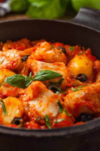 Geleneksel ispanyolca morina balığı. Domates sosunda haşlanmış patates, olivki ve fesleğen ile servis edilmiş. Ön görünüm. 