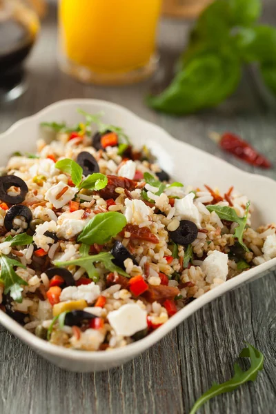 Kırmızı pirinçli moda öğle yemeği, sebze ve sebze karışımı. Ön manzara. Gri ahşap arka planda beyaz kasede servis ediliyor.. 