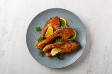 Parça parça sazan balığı, gri bir tabakta servis ediliyor. Parlak bir altyapısı var. Üst görünüm.