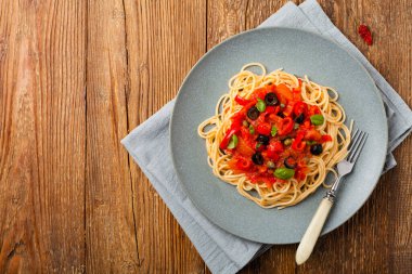 Domates ve zeytinli İtalyan spagetti alla Pultanesca. Et ve peynir olmadan servis edilir. Üst Manzara. Doğal ahşap zemin. 
