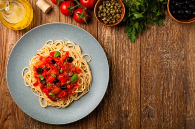 Domates ve zeytinli İtalyan spagetti alla Pultanesca. Et ve peynir olmadan servis edilir. Üst Manzara. Doğal ahşap zemin. 