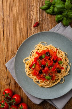 Domates ve zeytinli İtalyan spagetti alla Pultanesca. Et ve peynir olmadan servis edilir. Üst Manzara. Doğal ahşap zemin. 