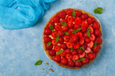 Mavi arka planda çilekli lezzetli bir tart. Üst görünüm.