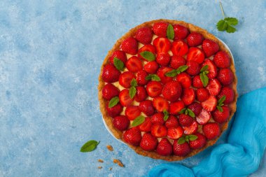 Mavi arka planda çilekli lezzetli bir tart. Üst görünüm.