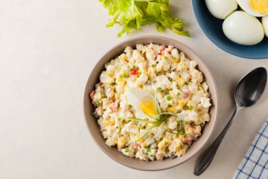 Kerevizli, turşulu, biberli ve mayonezli hafif yumurta salatası. Arka planda bir kasede servis edilmiş. Üst görünüm.