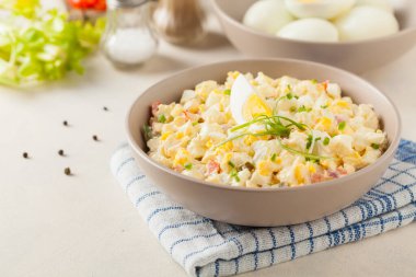 Kerevizli, turşulu, biberli ve mayonezli hafif yumurta salatası. Arka planda bir kasede servis edilmiş. Ön görünüm.