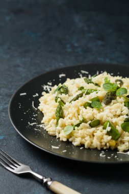 Klasik İtalyan pilavı ve kuşkonmaz. Ön manzara. Koyu mavi arkaplan.