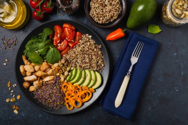 Kinoalı salata, avokado ve tavuk. Üst Manzara. Siyah bir tabakta servis edildi..