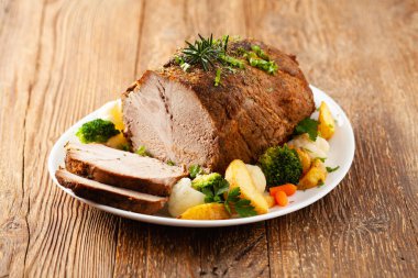 Tam pişmiş domuz boynu. Sebze ve fırında patatesle birlikte beyaz bir tabakta servis edilir..
