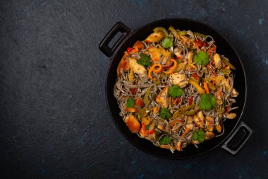 Siyah susamlı buğday eriştesi, tavuk ve sebzeli tavada kızartılmış. Üst görünüm.