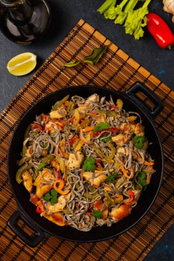 Siyah susamlı buğday eriştesi, tavuk ve sebzeli tavada kızartılmış. Üst görünüm.