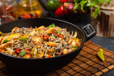 Siyah susamlı buğday eriştesi, tavuk ve sebzeli tavada kızartılmış. Ön görünüm.