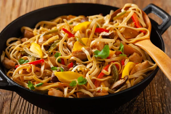 Fried chicken with mango and coconut milk with noodles. Prepared in a wok. Front view.