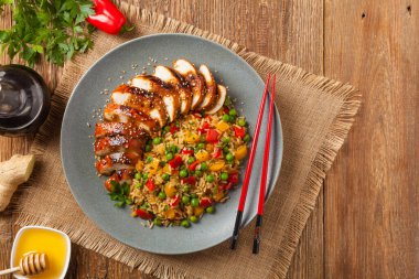 Teriyaki soslu ızgara tavuk göğsü. Kahverengi pirinç ve sebzelerle servis edilir. Üst Manzara. Düz yatıyordu.