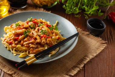 Shimeji mantarlı ve tavuklu geleneksel erişte. Bir tavada hazır. Gri bir tabakta servis edilmiş. Ahşap arka plan. Ön görünüm.