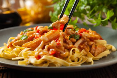 Shimeji mantarlı ve tavuklu geleneksel erişte. Bir tavada hazır. Gri bir tabakta servis edilmiş. Ahşap arka plan. Ön görünüm.