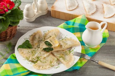 Ispanaklı hamur tatlısı, eritilmiş tereyağı ve doğranmış dereotu serpiştirilmiş. Ahşap arka plan. Beyaz tabak. 